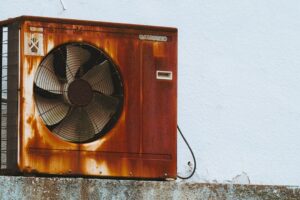 aging outdoor air conditioning unit with visible wear and rust, home backyard, natural lighting - how old is too old for an